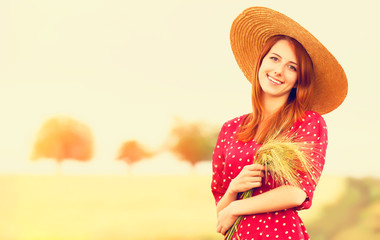 Redhead girl in red dress at wheat field