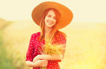 Redhead girl in red dress at wheat field