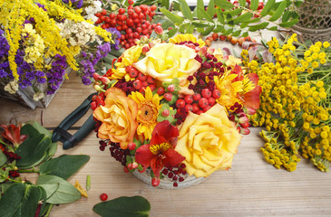 Bouquet of orange roses and autumn plants in vintage ceramic vas