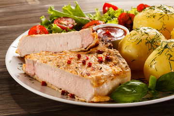 Fried pork chop, boiled potatoes and vegetable salad