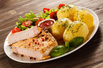 Fried pork chop, boiled potatoes and vegetable salad