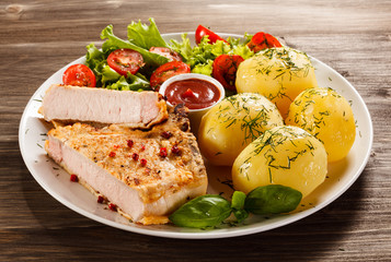 Fried pork chop, boiled potatoes and vegetable salad