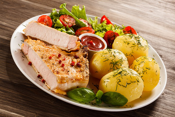 Fried pork chop, boiled potatoes and vegetable salad