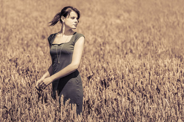 Beautiful young woman with pretty dress in a wide field of corn