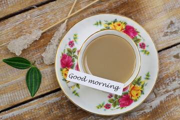 Good morning card with tea in vintage cup on wooden surface
