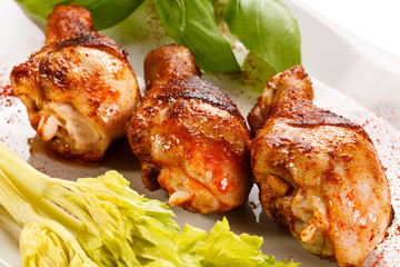 Grilled chicken legs and vegetables on white background