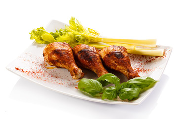 Grilled chicken legs and vegetables on white background