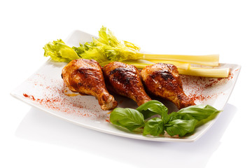 Grilled chicken legs and vegetables on white background