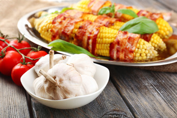 Grilled bacon wrapped corn on table, close-up