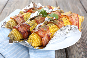 Grilled bacon wrapped corn on table, close-up
