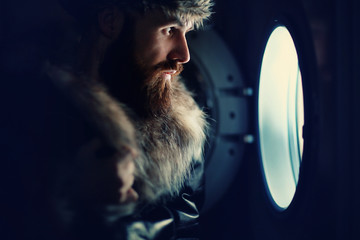 man looking through a porthole of a ship