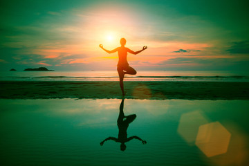 Silhouette yoga woman on sea coast at sunset