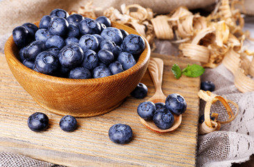 Wooden bowl of blueberries on cutting board on sacking napkin