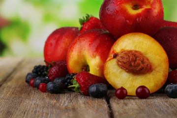 Peaches with berries on table on natural background