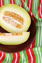 Melon on brown plate on tablecloth background
