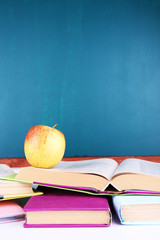 School supplies on table on blackboard background