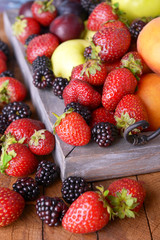 Ripe fruits and berries on tray on table close up