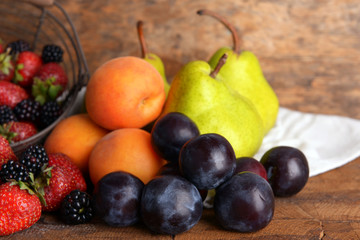 Ripe fruits and berries on tray on wooden background