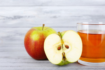 glass of apple juice and fresh apples on grey wooden table