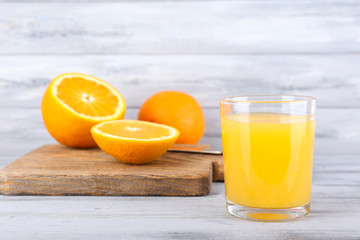 glass of juice with fresh orange on grey wooden table