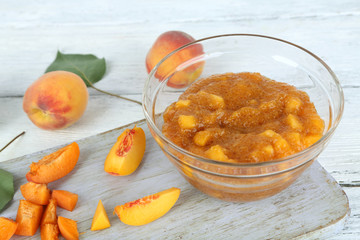 tasty peach jam with fresh peaches on wooden table