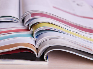 Magazines on wooden table on bright background