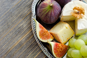 Brie, figs and grapes on a tray copy space