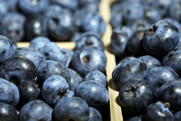 Tasty ripe blueberries in wooden crate, close up