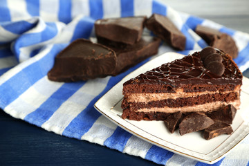 Chocolate cake on plate on color wooden background