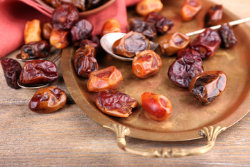 Tasty dates fruits on old metal tray, on wooden background