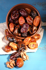 Tasty dates fruits in bowl, on blue wooden background