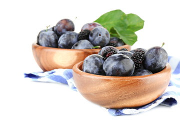 Ripe sweet plums in wooden bowls, isolated on white