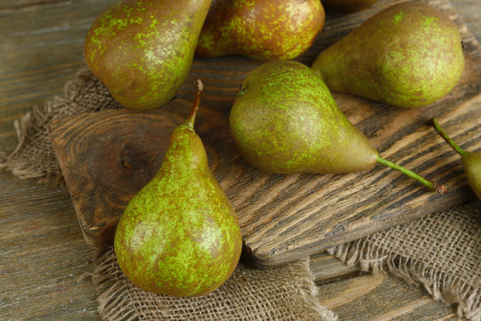 Ripe pears on cutting board, on wooden background
