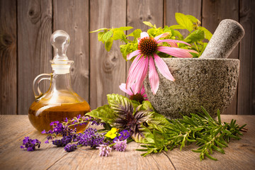 Healing herbs with mortar and bottle of essential oil