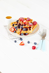 Golden waffles with berries and cup of honey wide