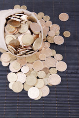 Fabric bag full of Ukrainian coins on wooden background