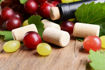 Wine bottle corks with grapes on table close-up