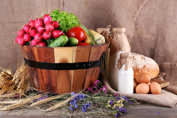 Big round wooden basket with vegetables, milk and bread
