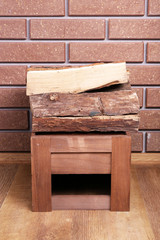 Wooden box of firewood on floor on brick background