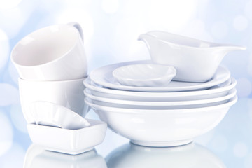White crockery and kitchen utensils, on light background
