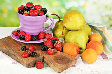 Ripe fruits and berries on table on bright background