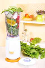 Blender with fresh vegetables on kitchen table