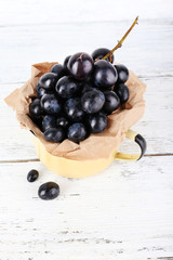 Purple grape in cup on wooden background