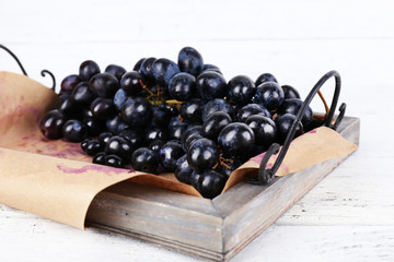 Purple grape on tray on wooden background
