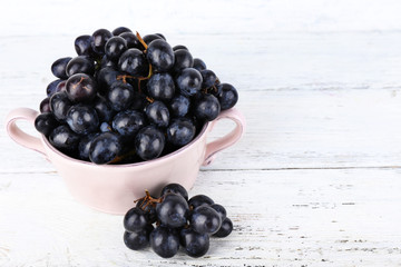 Purple grapes in bowl on wooden background