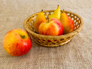 Fresh red apples and pears in a straw basket