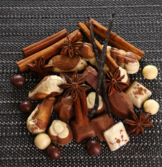 Different kinds of chocolates with spices on dark background