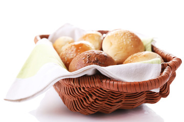 Tasty buns with sesame in wicker basket, isolated on white