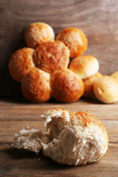 Tasty buns with sesame on color wooden background