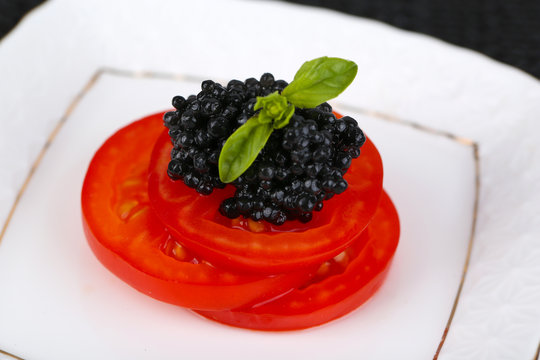 Slices of tomato with black caviar